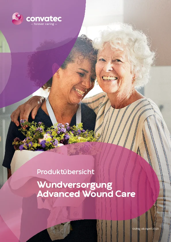 Eine ältere Frau umarmt ihre Pflegekraft und schenkt ihr Blumen. Beide Frauen lachen. 